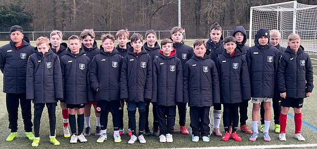 Die Fussball D2-Junioren der SG Bruchköbel in ihren neuen schwarzen Winterjacken vom Sponsor Odenwäller auf dem Sportplatz