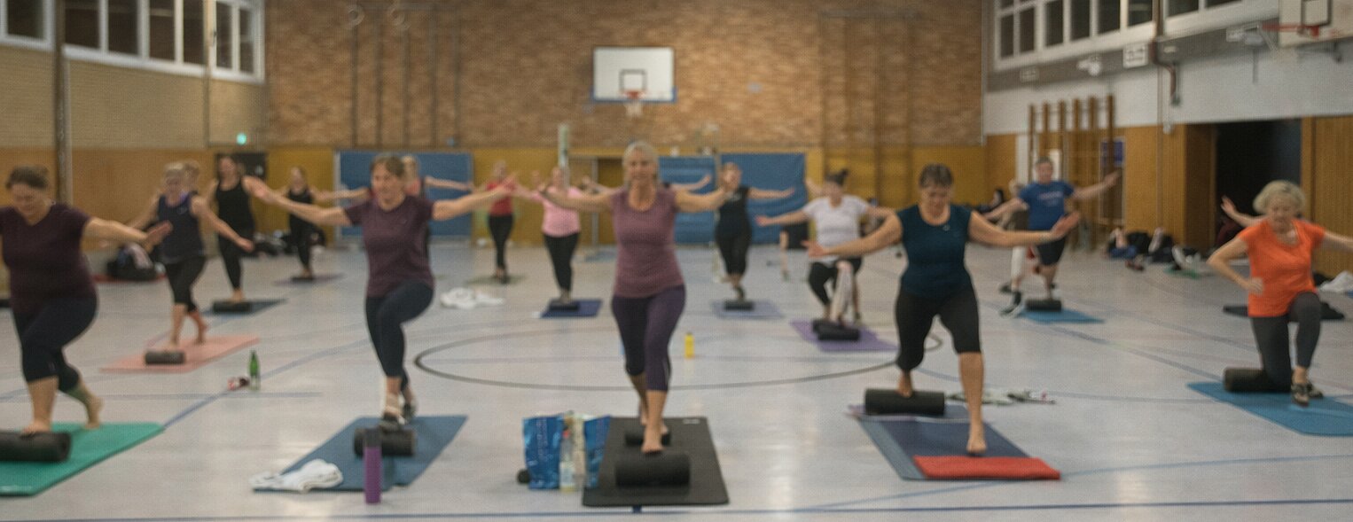 Sportler beim Athletiktraining mit Battle Ropes und Sprungübungen in einer lichtdurchfluteten Sporthalle.